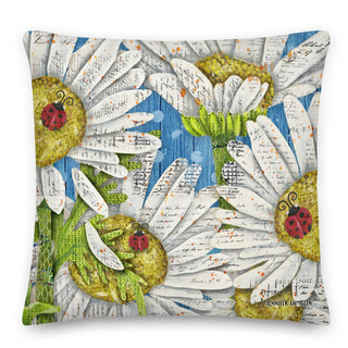 A throw pillow with whimsical daisies and ladybugs on  a blue sky background. Artwork by Jennifer Lambein. 