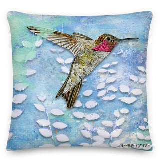 A throw pillow with a watercolor hummingbird amidst a summer meadow scene. Artwork by Jennifer Lambein. 