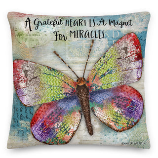 A colorful throw pillow with a butterfly and positive quote that says, "A grateful heart is a magnet for miracles". Artwork by Jennifer Lambein.