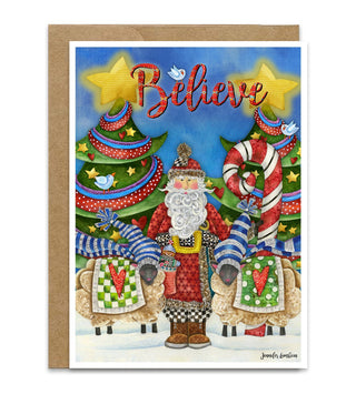 A Christmas greeting card with a kraft envelope, featuring a whimsical illustration of Santa Claus, sheep, a candy cane, decorated trees, birds and the word 'Believe' in red script against a blue sky. Artwork by Jennifer Lambein. 