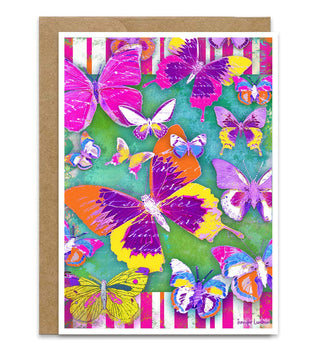 A greeting card featuring a vibrant, colorful butterfly pattern on a green background with pink striped borders, shown with a brown kraft envelope behind it. Artwork by Jennifer Lambein. 