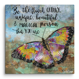 A canvas print with a colorful boho butterfly on it in the woods that says, "Be the flawed, quirky, unique, beautiful & magical person that you are." Artwork by Jennifer Lambein. 