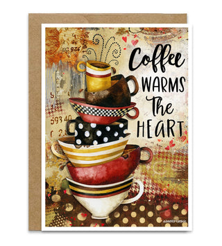 A greeting card with a kraft envelope, featuring an artistic stack of colorful coffee mugs and cups with the text 'Coffee WARMS THE HEART' on a textured, vintage-style background. Artwork by Jennifer Lambein. 