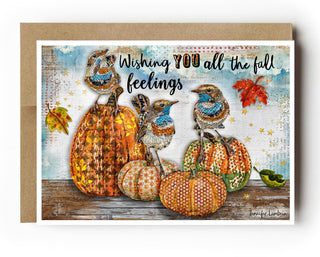Card with pumpkins, birds, and autumn leaves on a wooden background with text 'Wishing you all the fall feelings'.