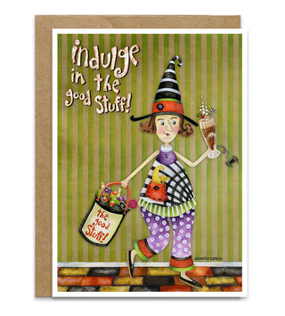 A greeting card with a brown kraft envelope, featuring a whimsical illustration of a witch walking with a basket of candy and a milkshake and spider, with the text 'indulge in the good Stuff!' on a green striped background. Artwork by Jennifer Lambein.