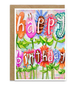 A whimsical and brightly colored birthday card with a kraft envelope, featuring a colorful watercolor-style floral design and the words 'happy birthday' in playful lettering. Artwork by Jennifer Lambein. 