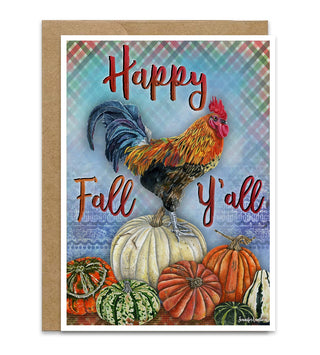 An autumn-themed greeting card with a kraft envelope, featuring a colorful illustration of a rooster standing on pumpkins with the text 'Happy Fall Y'all' on a plaid and blue patterned background. Artwork by Jennifer Lambein. 