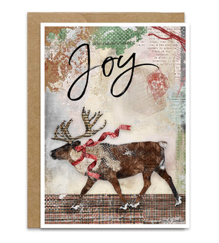 A Christmas greeting card featuring a collage-style illustration of a brown reindeer wearing a red bow and patterned scarf, with the word 'Joy' in black script above. The card has a white border and is shown with a kraft envelope behind it on a light gray background. Artwork by Jennifer Lambein. 