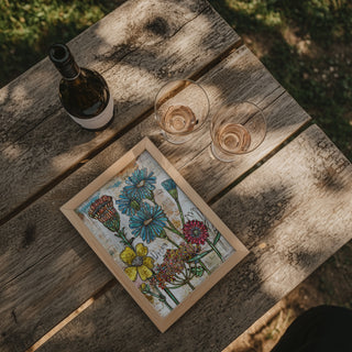 Wooden table with a bottle, two glasses, and a floral painting.