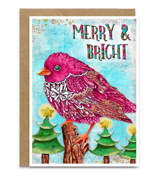 A sChristmas greeting card with a kraft envelope, featuring a pink bird perched on a tree stump against a light blue textured background with trees and stars, with the words “MERRY & BRIGHT” at the top. Artwork by Jennifer Lambein, 
