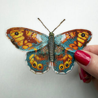 Bright orange and teal butterfly sticker with wildflowers. 