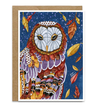 A greeting card featuring a detailed owl illustration on a starry night sky background, shown with a brown kraft envelope behind it on a white background. Artwork by Jennifer Lambein.