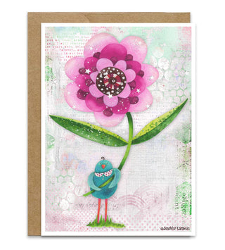 A greeting card with a brown kraft envelope behind it, featuring a whimsical illustration of a large pink flower with green leaves and a small blue bird on a textured pastel background. The artist's name, Jennifer Lambein, is printed in the lower right corner.