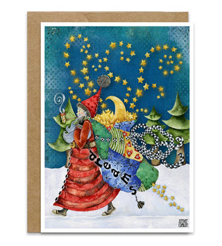 A greeting card featuring a whimsical illustration of Santa in a red striped coat carrying a blue bag labeled 'Dreams', surrounded by stars, trees, and holiday motifs, shown with a kraft envelope behind it on a white background. Artwork by Jennifer Lambein. 