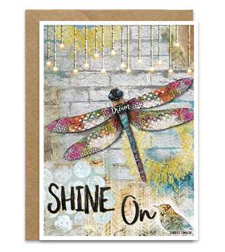 Greeting card with a dragonfly illustration and 'Shine On' text on a decorative background.