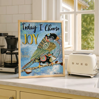 Framed artwork with a bird illustration and 'Today I Choose Joy' text on a kitchen counter.