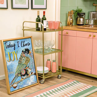 Kitchen with a gold bar cart, pink cabinets, and a framed picture of a swirly bird on a blue background.