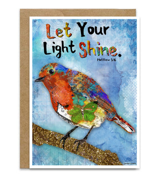 A greeting card with a kraft envelope behind it, featuring a colorful bird collage on a blue textured background with the text 'Let Your Light Shine. Matthew 5:16'. Artwork by Jennifer Lambein. 